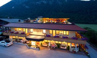 A charming hotel with blooming plants and an inviting atmosphere. In the background, mountains can be seen, providing a picturesque backdrop.