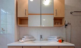 A modern bathroom with a sink and a mirror. Towels and a flower are decoratively placed on the sink.