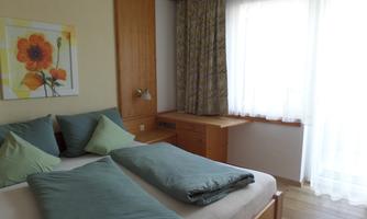 A modern bedroom with two beds and cozy pillows.  
Large windows provide plenty of natural light and an inviting atmosphere.