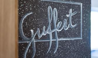 A lettering with the word "Gulfert" on a textured wall. The font is white and stands out from the dark surface.