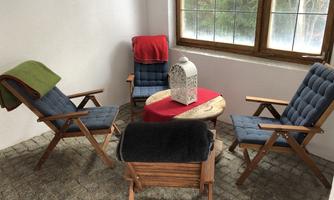 A cozy retreat with two comfortable chairs and a small table. The atmosphere is enhanced by a warm blanket and natural light from a window.