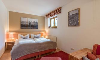 A cozy bedroom with two beds, warm colors, and art on the wall. The decor is modern and inviting, ideal for relaxing nights.