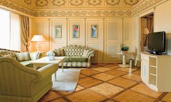 An elegant room with green sofas and a TV. Large windows let in plenty of light and create a friendly atmosphere.