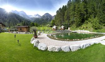 An idyllic landscape with a green lawn and a clear pond. In the background, high mountains and a tranquil atmosphere can be seen.