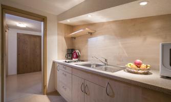 A modern kitchen unit with bright wooden surfaces and a sink. Fresh fruit and a coffee machine are on the countertop.