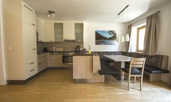 A modern kitchen with light cabinets and wood paneling. A cozy dining area with a large window and a view outside.