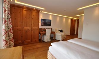 A cozy room with two beds, wooden-paneled walls, and a desk. The soft lighting and modern style create an inviting atmosphere.