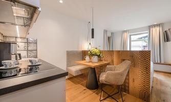 A modern kitchen with a cozy dining area. The table is beautifully decorated with flowers, and the decor is bright and inviting.