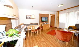 A bright and cozy kitchen with a dining area and a sitting corner. The decor is modern and welcoming, featuring wooden details and plenty of natural light.