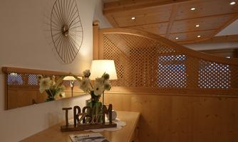 An elegant room with wood paneling and warm lighting. Flowers and a decorative sculpture are on the dresser.