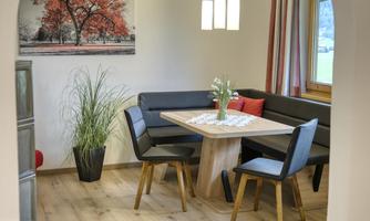 A cozy dining area with an elegant table and benches. Large windows provide plenty of natural light and a pleasant atmosphere.