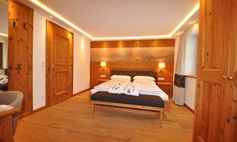 A modern room with wooden walls and a double bed. The soft lighting creates a cozy atmosphere.