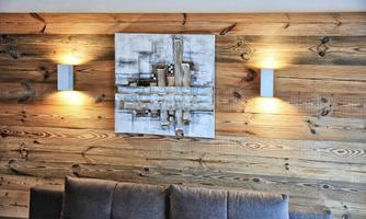 A modern living room with wood paneling and soft wall lights. An abstract painting hangs above a gray sofa.
