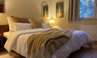 A cozy bedroom with a large bed and soft pillows. Soft light and warm colors create a relaxed atmosphere.