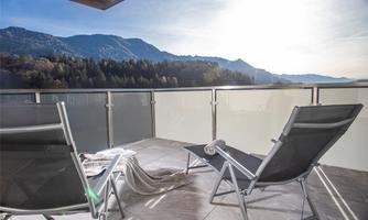 A beautiful balcony with two loungers and a view of the mountains. The sun is shining and creating a relaxed atmosphere.