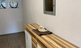A bright hallway with a wooden dresser and a mirror. The walls are painted in neutral tones.