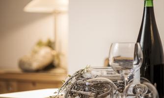 A stylish table decoration with a bottle of drinks and glasses. In the background, there is a soft lighting.