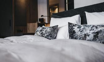 A cozy bedroom with a large bed and soft pillows. The modern decor creates a relaxed atmosphere.