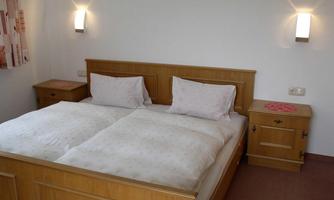 A simple bedroom with a double bed and two nightstands. The walls are bright and well-lit.