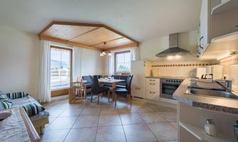 A cozy kitchen with a dining area and a large window front. The room is bright and furnished in a modern style.