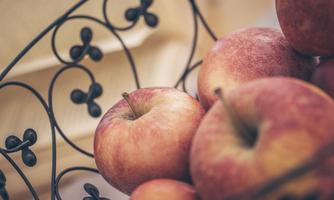 A basket of fresh apples in various shades of red. The apples are grouped together and are slightly shiny.