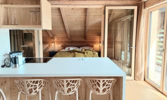 A modern interior with a kitchenette and a cozy bedroom. The wood paneling provides a warm atmosphere.