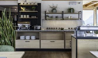 A modern kitchen with wooden shelves and elegant tableware. Plants and a bright, inviting atmosphere give the room freshness.