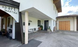 A modern house with an inviting entrance and a terrace. Next to it is a garage with a wooden door.