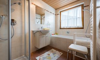 A modern bathroom with a shower and bathtub. Bright tiles and a window create a friendly atmosphere.