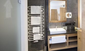 A modern bathroom with elegant design. It features a sink, towels, and a large mirror wall.