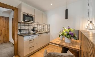A modern kitchen with bright cabinets and a stylish dining table. There are fresh flowers in a vase and a cozy atmosphere.