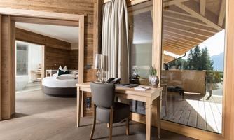 A modern chalet with wooden cladding and large windows. The space is bright and inviting, with a view of nature.