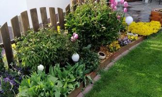 A beautiful garden area with colorful flowers and a well-maintained lawn. Nearby is a decorative fence and some garden ornaments.