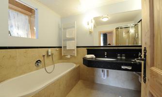 A modern bathroom with a bathtub and a double sink. Bright colors and windows create a friendly atmosphere.