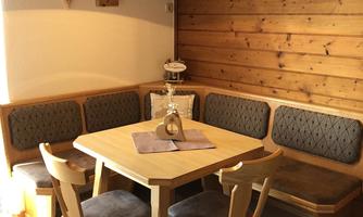 A cozy dining area with a wooden table and chairs. The walls are made of wood, and there is a pleasant lighting.