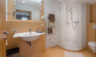 A modern bathroom with a shower and sink. Bright tiles and a spacious mirror surface create an inviting atmosphere.