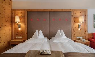 A cozy hotel room with two single beds and wood paneling. The beds are equipped with fresh bed linens and decorative pillows.