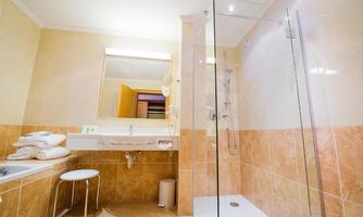 A modern bathroom with a glass shower and a washbasin. Beige tiles and fresh towels create an inviting atmosphere.