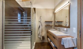 A modern bathroom with a shower and an elegant vanity. Wood and stone accents create a warm atmosphere.
