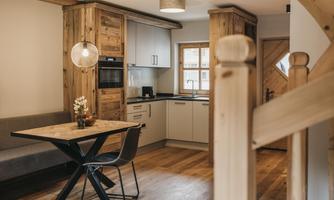 A modern kitchen with wooden details and a dining area. The room is designed to be bright and welcoming.