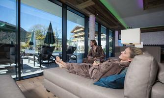 A relaxing wellness area with large windows overlooking the terrace. Two people in bathrobes enjoy the peaceful atmosphere.