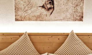 A cozy bedroom with two pillows and a wall decoration of a deer head. The pillows are checked and give the room a rustic atmosphere.