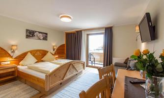 A cozy room with wooden accents and two beds. The room features a balcony and modern amenities.