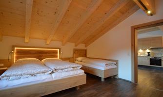 A cozy bedroom with two wooden beds and a tasteful roof. The room has a warm, inviting look with soft lighting.