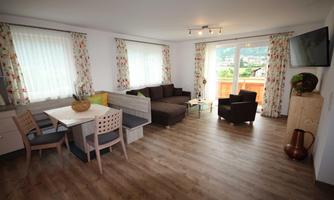 A bright living room with modern furniture. Large windows provide plenty of daylight and a view of nature.