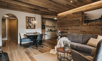 A cozy living room with wood paneling and a neutral tone. An elegant table and a comfortable couch invite relaxation.