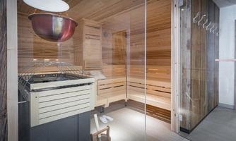 A modern sauna with wooden cladding and a stove. The surroundings are clean and inviting, ideal for relaxing.