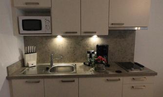 A modern kitchen with beige cabinets, a microwave, and a small sink. The lighting creates a pleasant atmosphere.