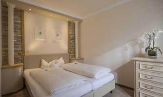 An elegant bedroom with a large double bed and a bright, cozy atmosphere. The room features decorative elements and a beautiful nightstand.