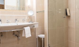 A modern bathroom with a walk-in shower and a large mirror. The walls are painted in light colors that create a clean and inviting atmosphere.